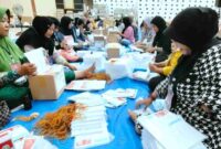 Sejumlah ibu-ibu tampak khusyu saat melakukan pelipatan surat suara Pilkada 2024 di Gudang Logistik KPU Situbondo, (Ist).