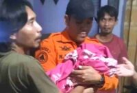 Terlihat petugas dari BPBD Kota Surabaya saat mengevakuasi bayi yang ditemukan dari atap rumah warga, (Ist).