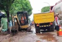 Petugas mebersikan sisa material banjir menggunakan ekskavator,(Ist).