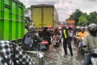 Polisi mengatur lalu lintas kendaraan di ruas jalan yang tergenang banjir (Ist).
