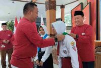 Bupati Situbondo Yusuf Rio Wahyu Prayogo secara simbolis mengenakan atribut kepada salah satu peserta sebelum keberangkatan ke Jumbara PMR X tingkat Jawa Timur di Pendopo Rakyat Situbondo, Senin (08/09/2025), (Fia Rahma/Liputansatu.id).
