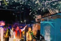 Petugas kepolisian bersama aparat desa meninjau rumah warga yang mengalami kerusakan akibat diterjang angin puting beliung di Desa Tanjungrejo, Kecamatan Singgahan, Kabupaten Tuban, Senin (29/9/2025) malam, (Assayid Annazili/Liputansatu.id).