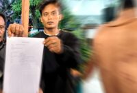 Korban salah tangkap, Muhammad Rifai alias Radit, didampingi ayahnya saat menunjukkan bukti laporan ke Polda Jawa Timur serta sejumlah bekas luka di tubuhnya. Keluarga menolak upaya damai dan meminta proses hukum dilanjutkan, (Assayid Annazili/Liputansatu.id).