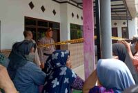 Petugas kepolisian berjaga di lokasi rumah korban penemuan satu keluarga meninggal dunia di Desa Demung, Kecamatan Besuki, Situbondo, sambil menunggu proses olah TKP oleh Tim Inafis Polres Situbondo, (Fia Rahma/Liputansatu.id).