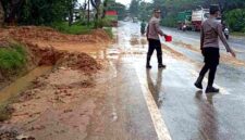 Petugas kepolisian membersihkan lumpur dan pasir kuarsa yang tercecer di jalur nasional Pantura Tuban. Ceceran limbah dari aktivitas pencucian pasir ini kerap membuat jalan licin dan membahayakan pengguna jalan, memicu sorotan terhadap kepatuhan izin, pengelolaan lingkungan, dan lemahnya pengawasan pemerintah daerah, (Assayid Annazili/Liputansatu.id).