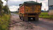 Kondisi jalan rusak parah di jalur Merakurak–Jenu, Tuban, dipenuhi lubang besar dan genangan air saat dilintasi truk bermuatan berat, memicu kekhawatiran keselamatan pengguna jalan, (Aji Swasto/Liputansatu.id).