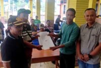 Perwakilan warga Desa Menyunyur menyerahkan dokumen tuntutan kepada pihak terkait di balai desa terkait kerusakan jalan akibat aktivitas truk pengangkut urukan KDMP di Kecamatan Grabakan, Tuban, (Assayid Annazili/Liputansatu.id).