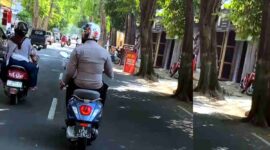 Anggota Polsek Singgahan terekam mengendarai sepeda motor sambil mengenakan seragam dinas di Jalan Basuki Rahmat, Tuban, (Assayid Annazili/Liputansatu.id).