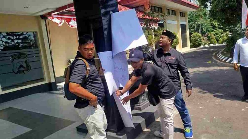 Beberapa wartawan menempel poster di tiang Mapolresta Tuban sebagai bentuk protes intimidasi ( gambar : Assa Annazili)
