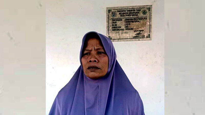 Rusmiati, warga Desa Pongpongan, Kecamatan Merakurak, Kabupaten Tuban, menunjukkan rumah bantuan RTLH yang telah dihuni keluarganya selama enam tahun. Meski hidup dari penghasilan suami sebagai tukang becak, keluarganya kini masuk Desil 6 DTSEN dan khawatir kehilangan bantuan sosial. (Aji Swasto/Liputansatu.id).
